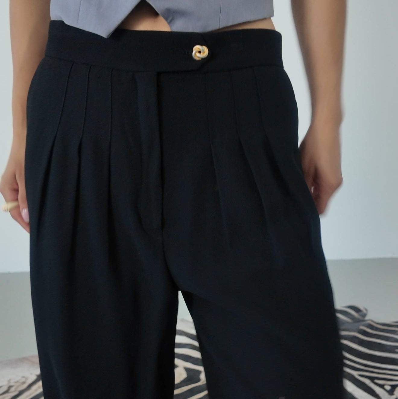 Black wide-leg pants worn by a person with a zebra-patterned rug in the background